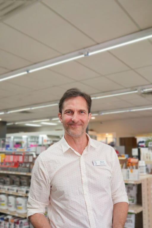 Dave Downie stands in a pharmacy aisle smiling
